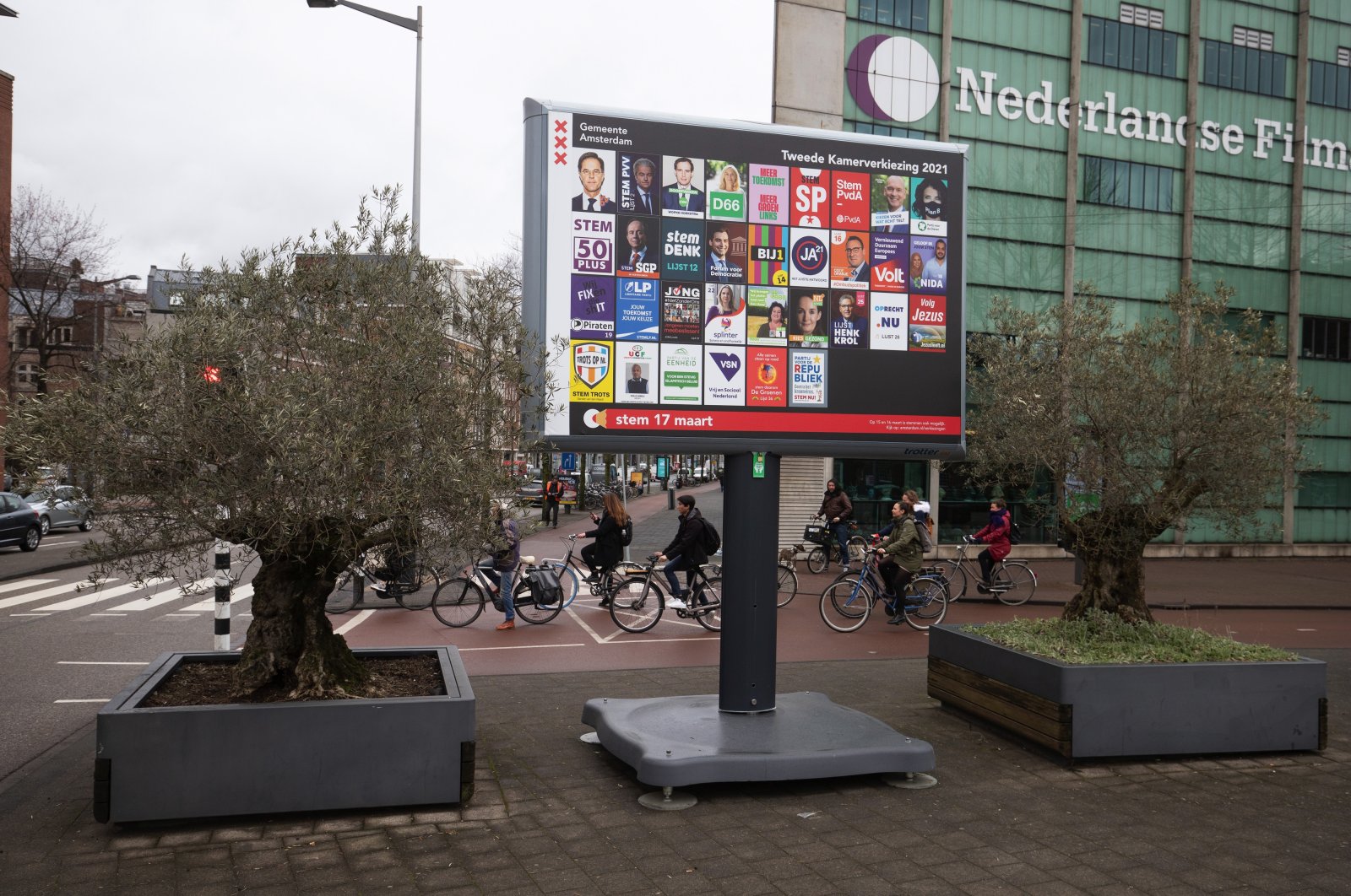 9 Mart 2021 Salı günü Amsterdam, Hollanda'da bir reklam panosundaki Hollanda siyasi parti seçim kampanyası afişlerinin yakınında bir yol geçişinde bisikletliler. (Getty Images)