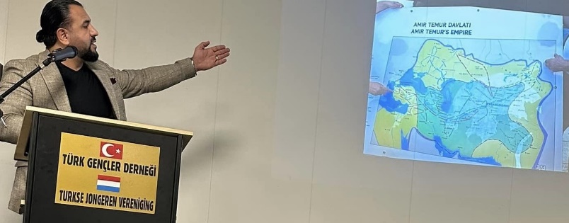 Afbeelding met tekst, kleding, Redenaar, Spreken in het openbaar Automatisch gegenereerde beschrijving