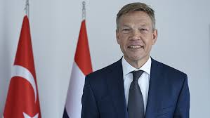 Afbeelding met pak, persoon, Menselijk gezicht, kleding Door AI gegenereerde inhoud is mogelijk onjuist.